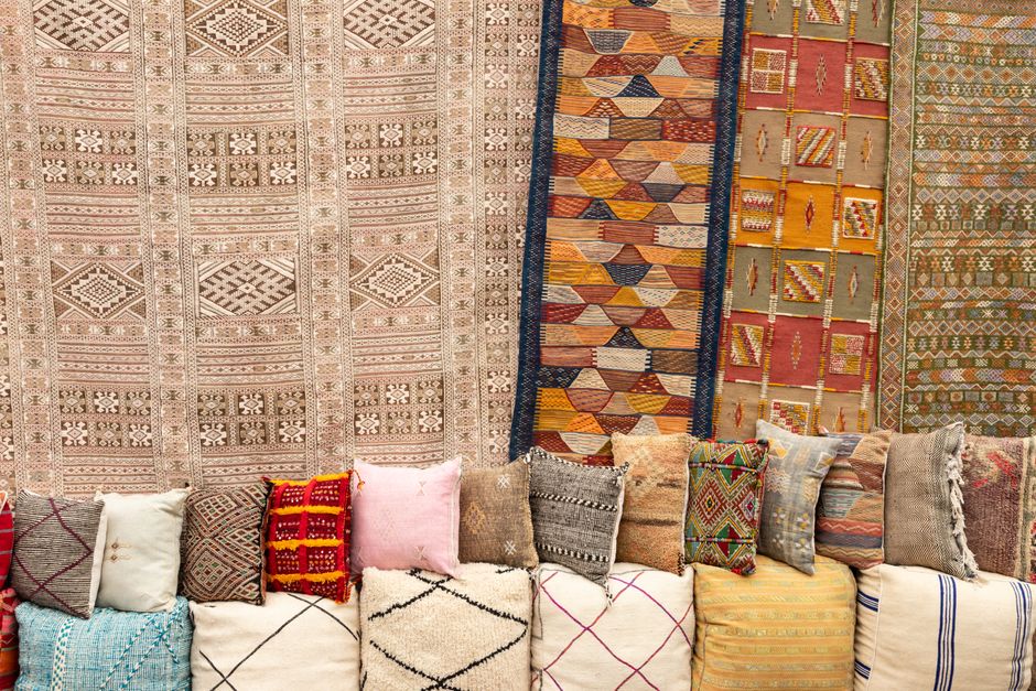 Vibrant Moroccan textiles and traditional patterns featuring colorful rugs and pillows on display.